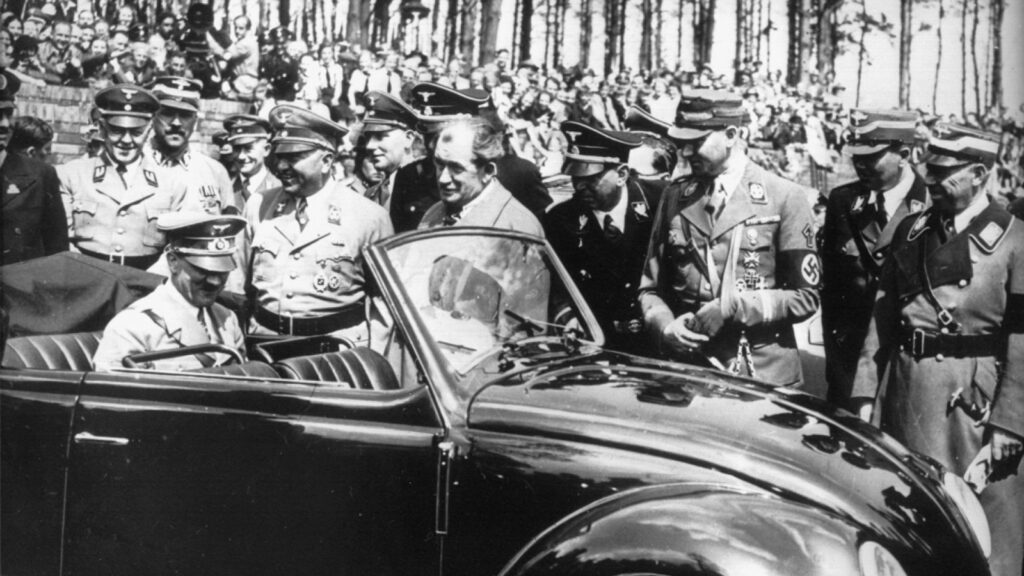Ferdinand Porsche shows Hitler the benefits of the Beetle.